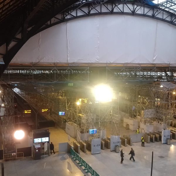 Viajeros en la estación de Valencia bajo la cimbra protegida con lonas durante la obra