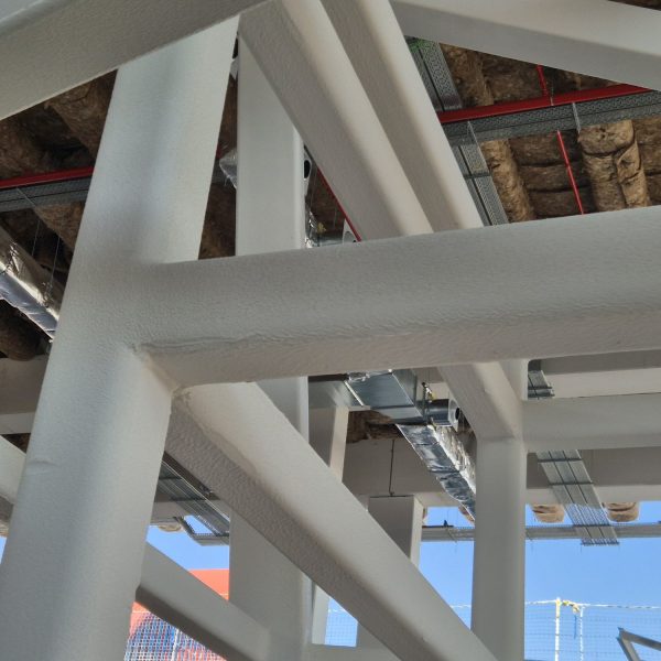 Nudos de vigas metálicas con pintura blanca bajo el techo de la estación de Chamartín